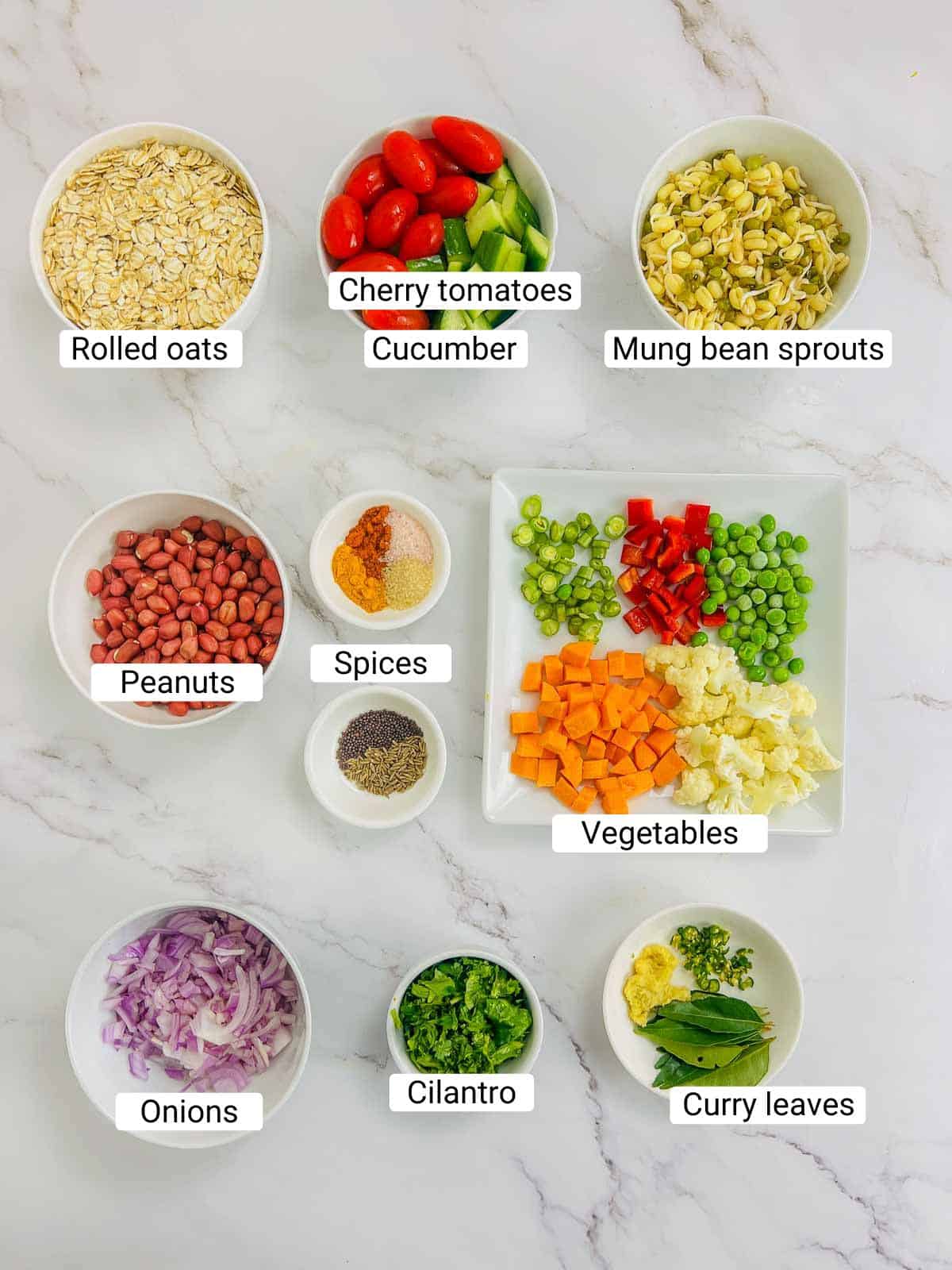 Ingredients to make oats upma breakfast bowl on a white surface.