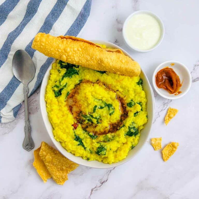 Palak khichdi topped with tempering and papad.