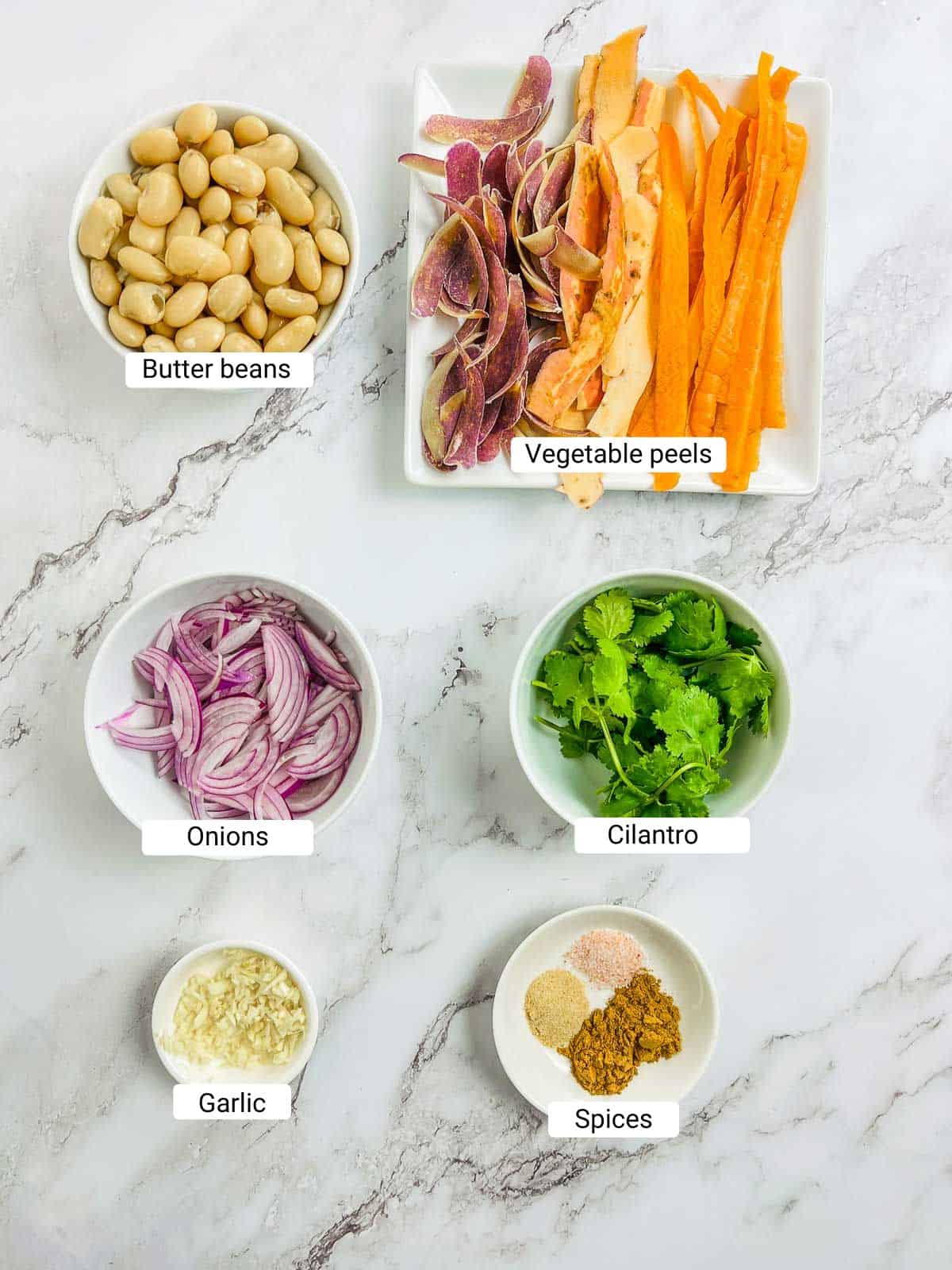 Ingredients to make vegetable peel dip and curried bean chips on a marble surface.