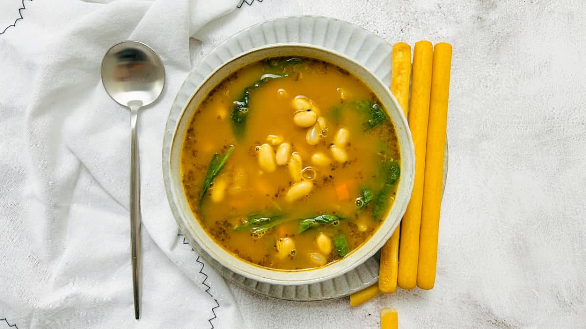 White bean soup in a bowl served with breadsticks.