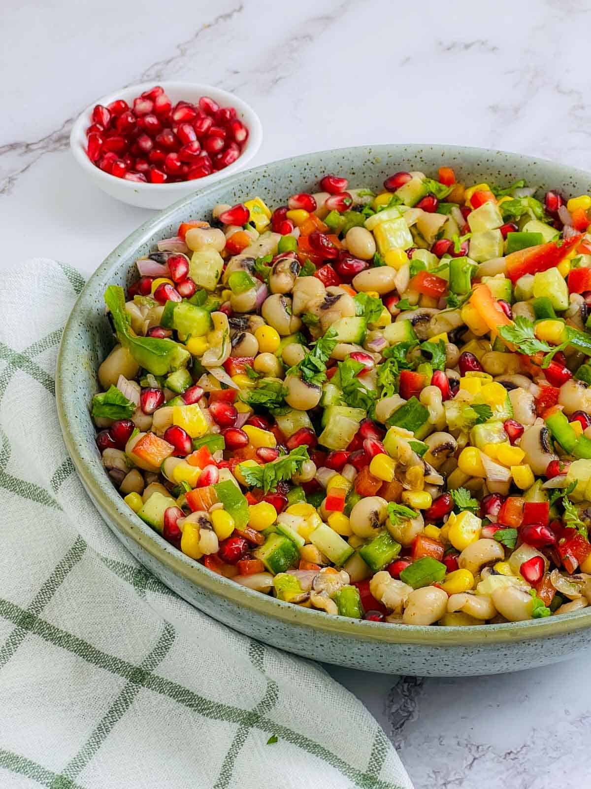 Black-eyed peas salad with pomegranate seeds in the background.