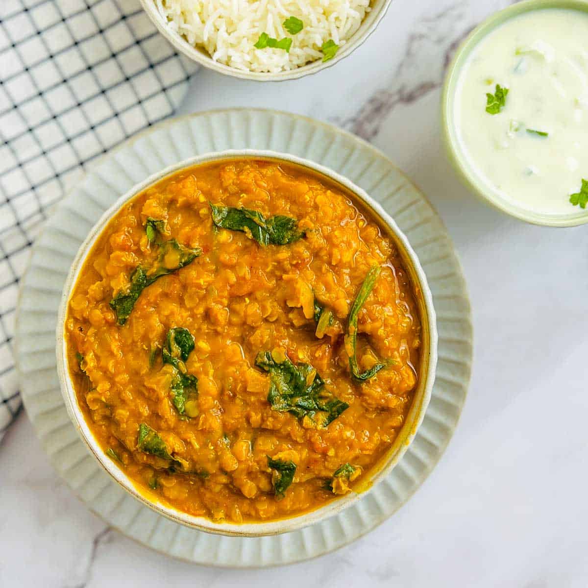 Red lentil dal served with rice and raita.