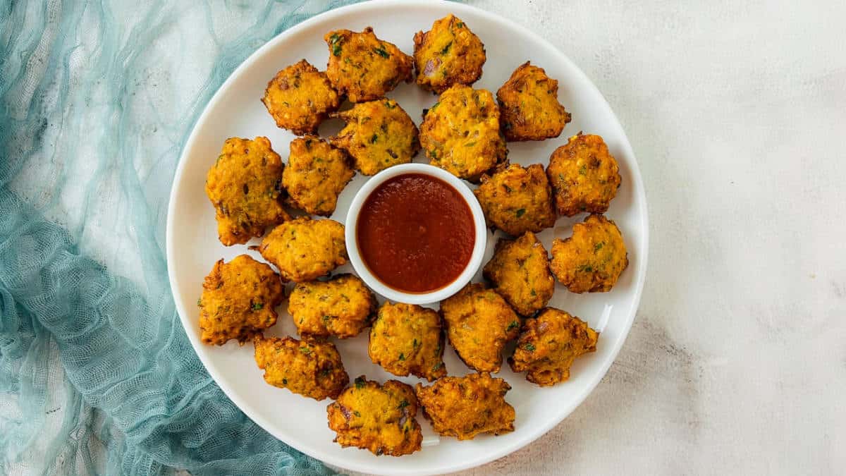 Red lentil fritters on a white plate served with tomato ketchup.