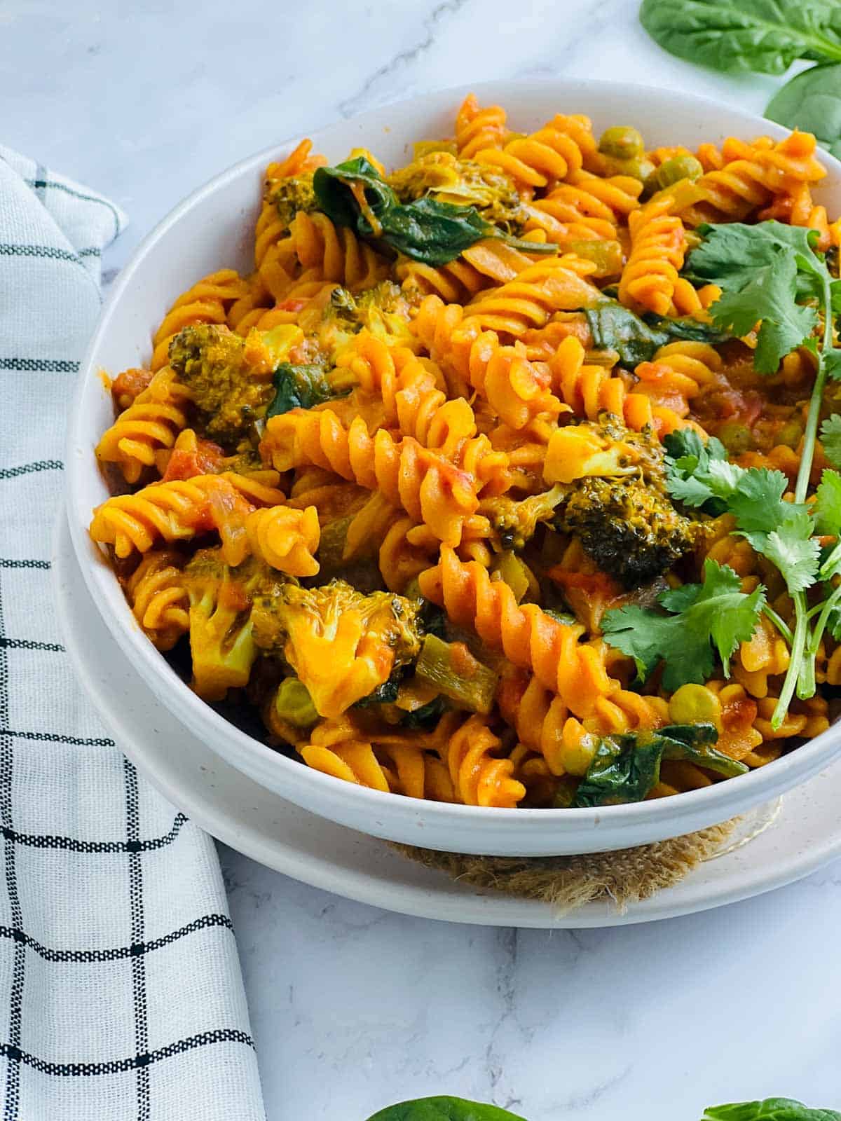Red lentil pasta in a white bowl topped with cilantro.