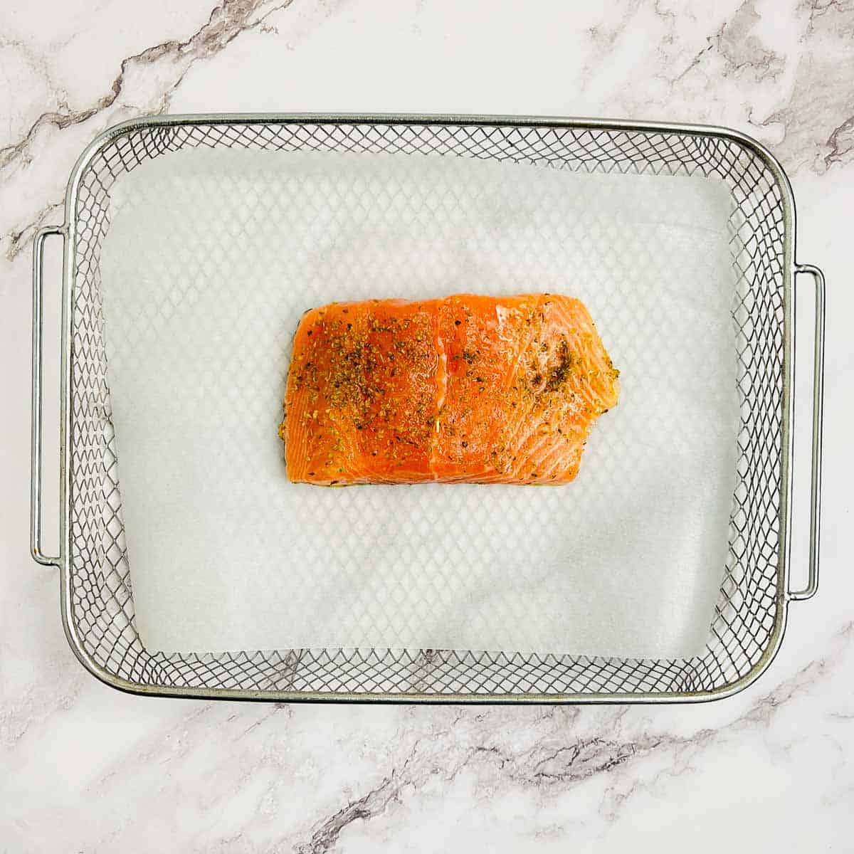 Marinated salmon fillet in the air fryer basket.