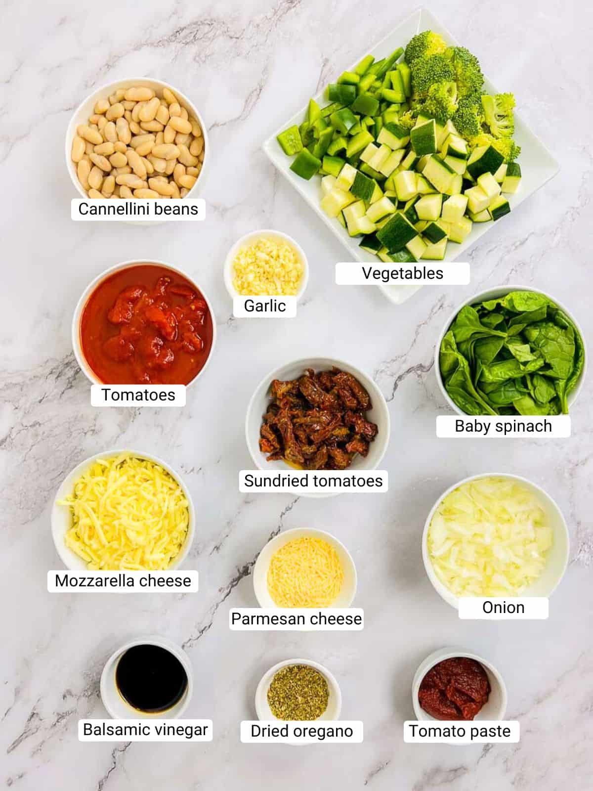 Ingredients to make bean and tomato bake on a marble surface.