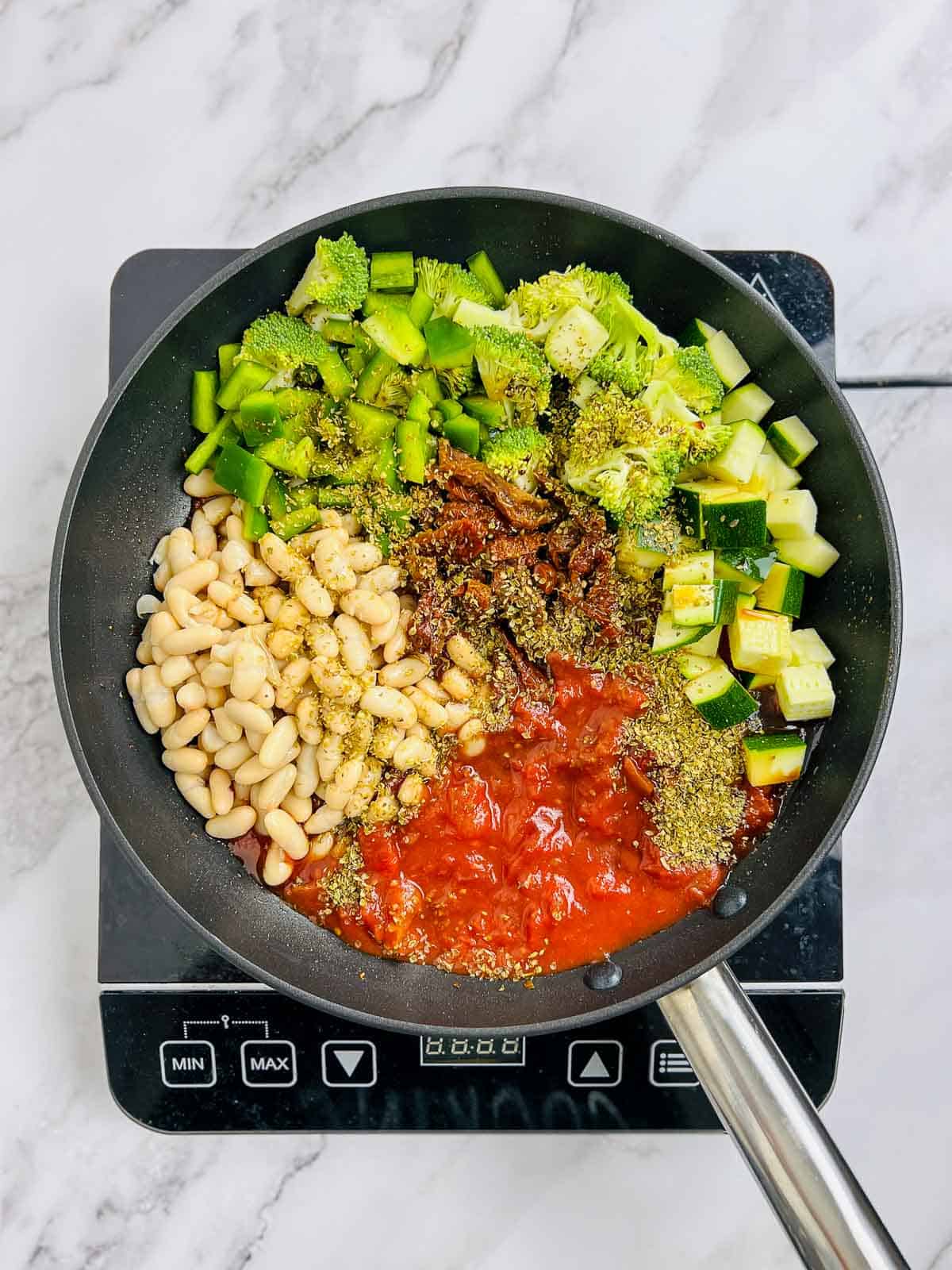 White beans, veggies, tomatoes, and spices in the skillet.