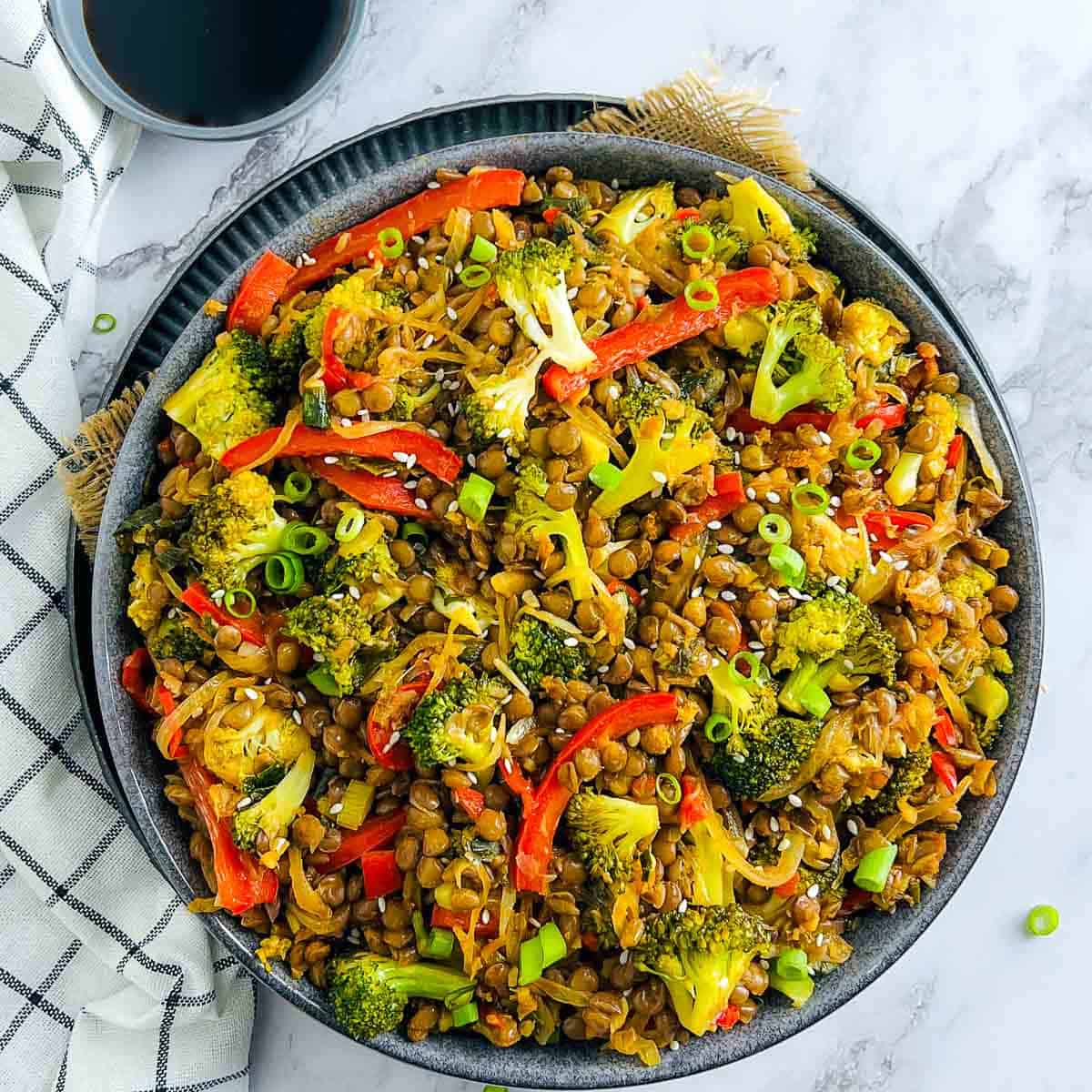 Broccoli lentil stir fry in a green bowl garnished with green onions.