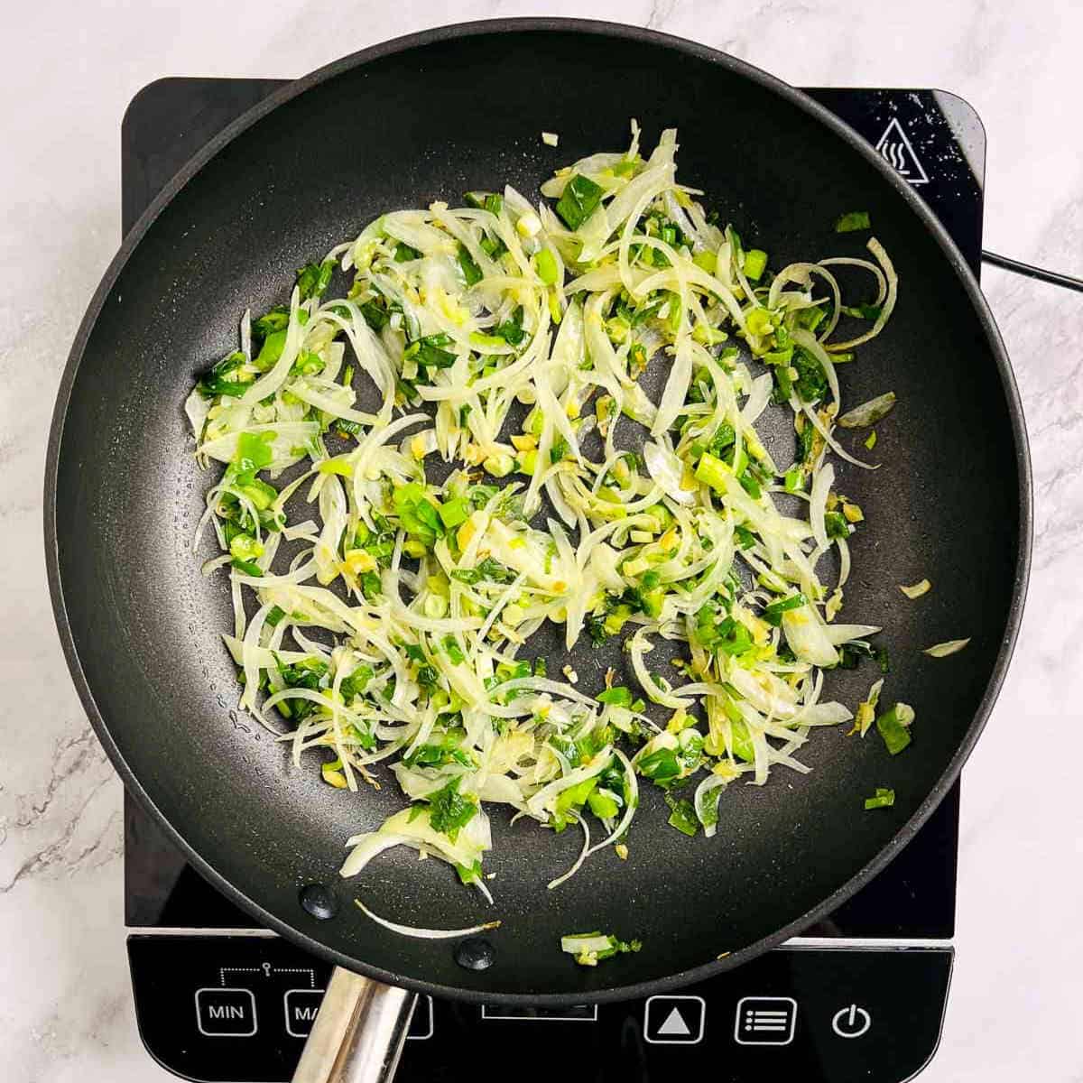 Sauteed onion, ginger, garlic, and scallions in the frying pan.