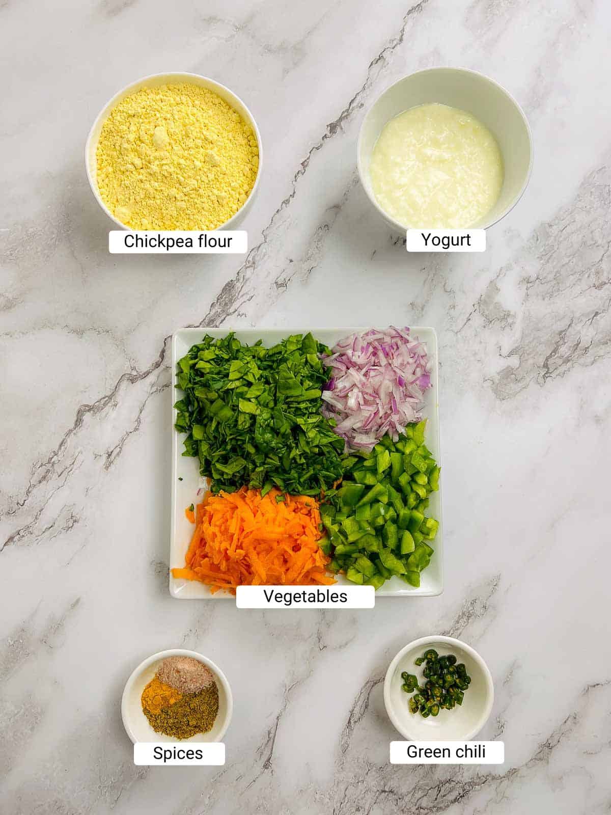 Ingredients to make chickpea flour pancakes on a marble surface.