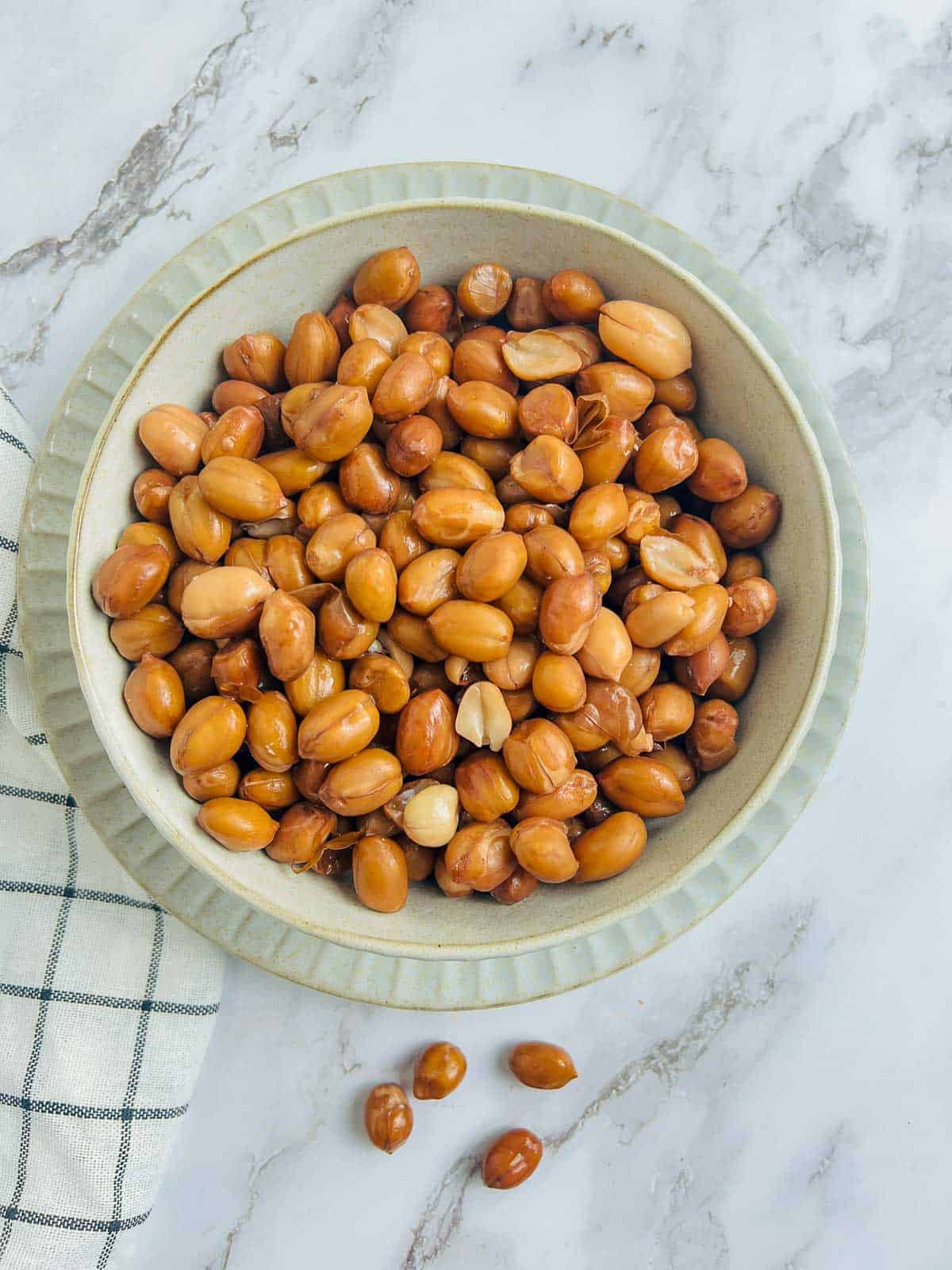 Boiled shelled peanuts in a white bowl.