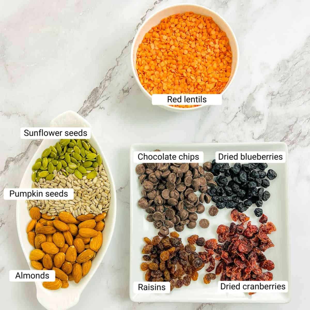 Ingredients to make trail mix on a marble surface.