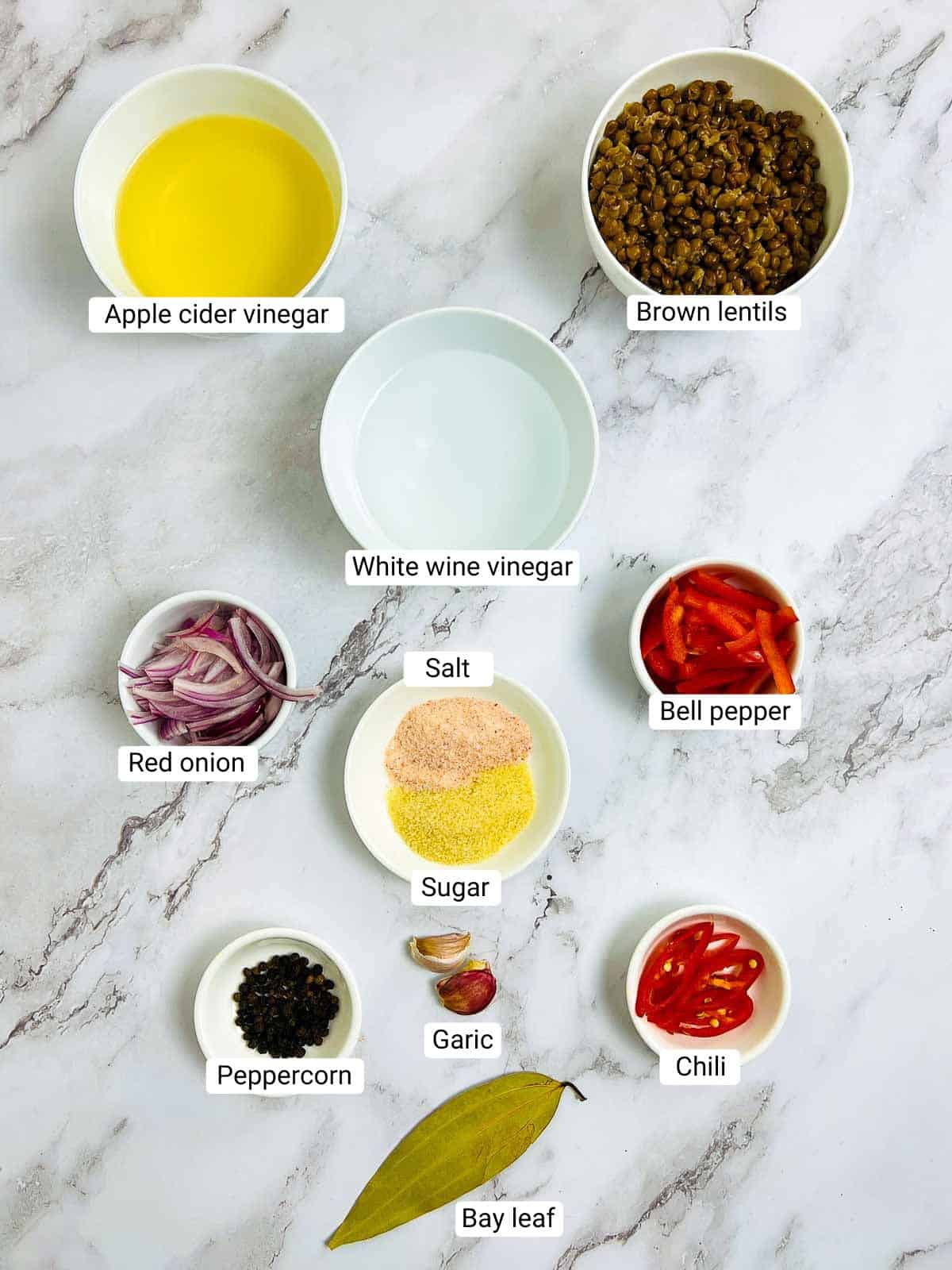 Ingredients to make pickled lentils on a marble surface.