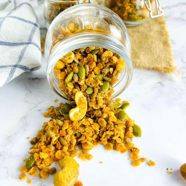 Red lentil granola spilling from a glass jar.