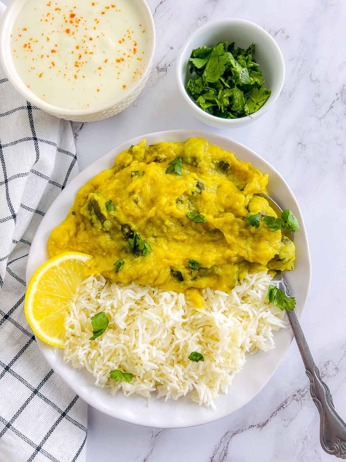 Zucchini dal and rice served on a white plate with spoon.
