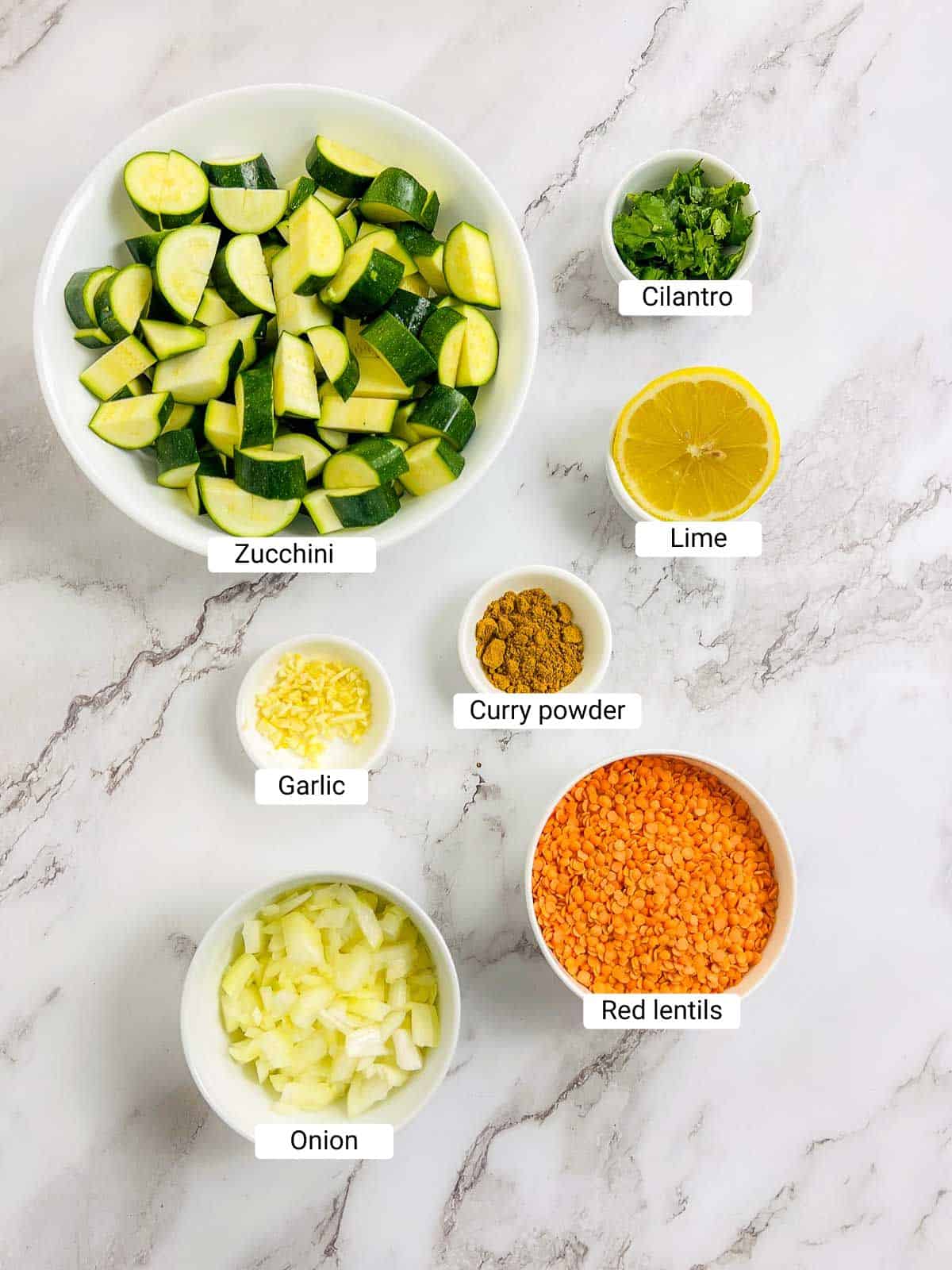 Ingredients to make zucchini dal on a marble surface.