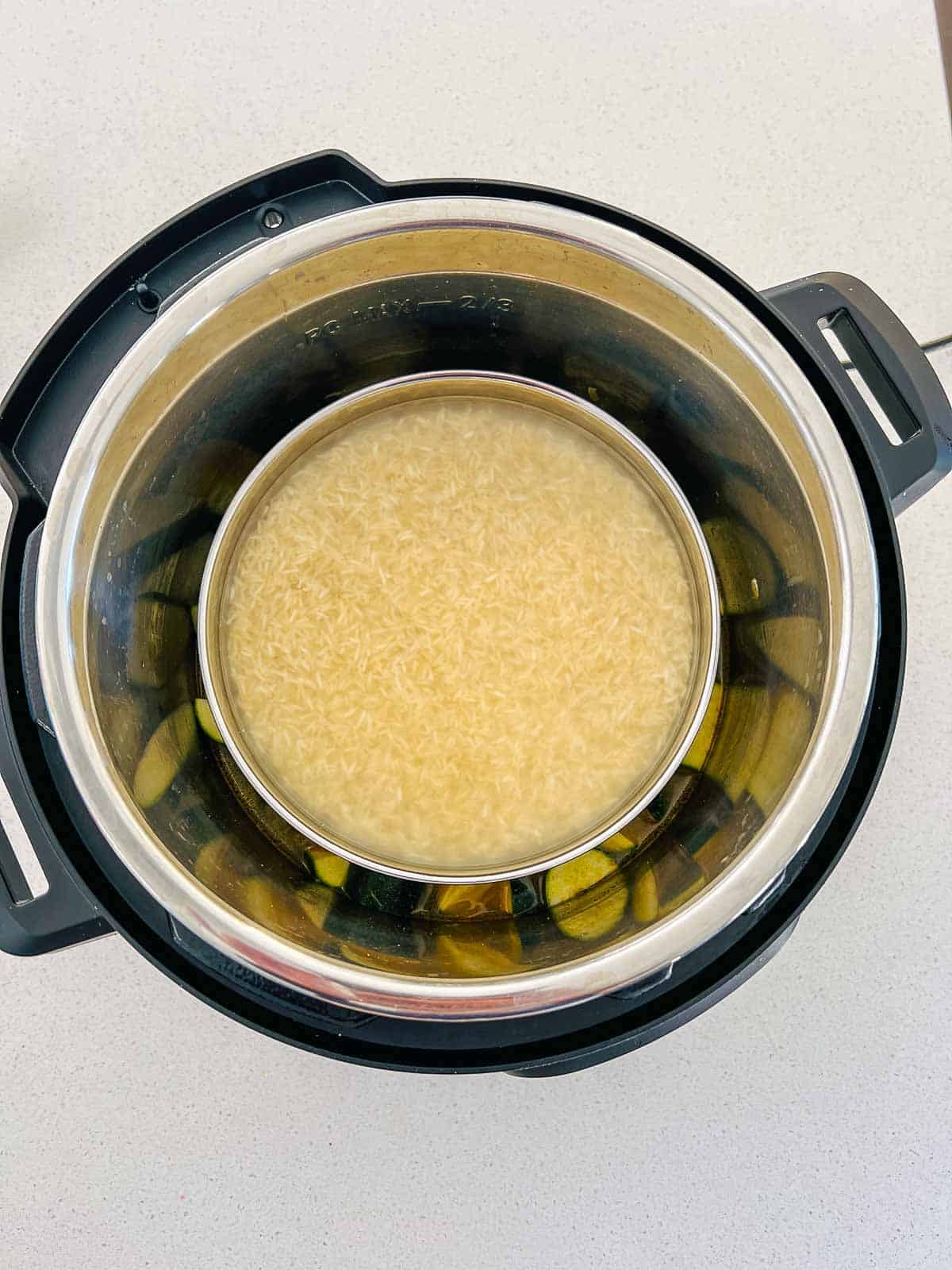 Rice-water bowl placed on a trivet over the dal and zucchini in the Instant Pot.