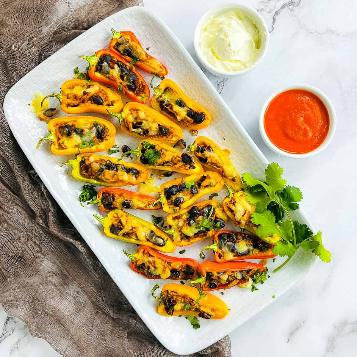 Chicken taco stuffed sweet peppers on a rectangular plate.