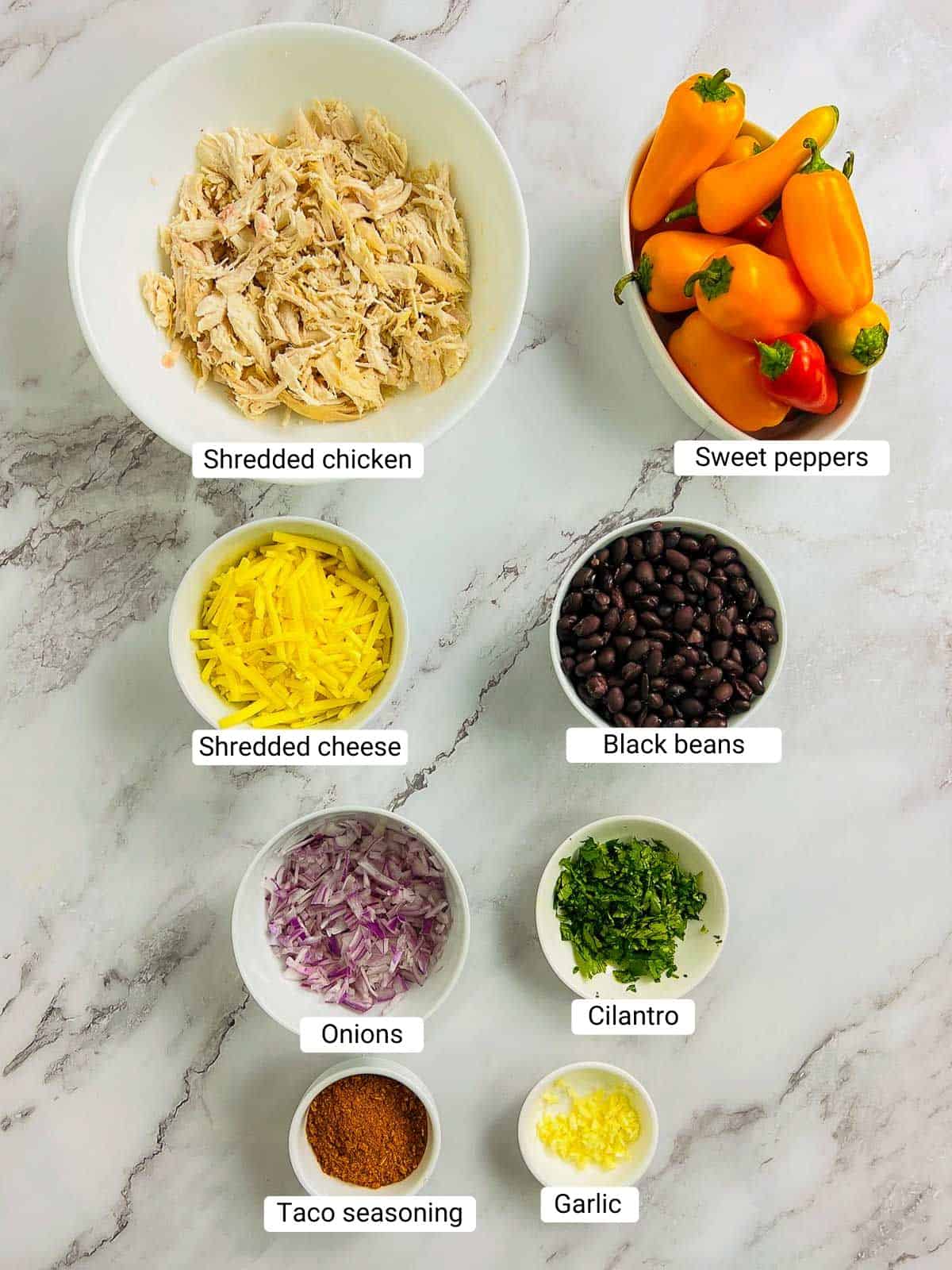 Ingredients to make stuffed sweet peppers on a marble surface.