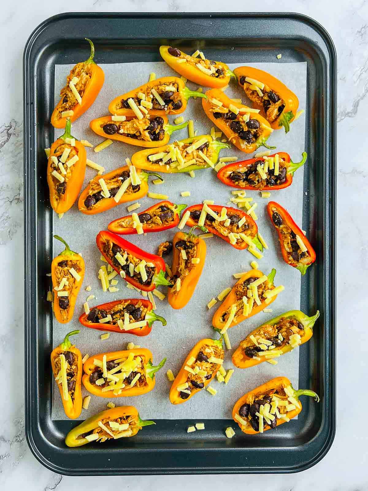 Stuffed peppers on a lined baking sheet.