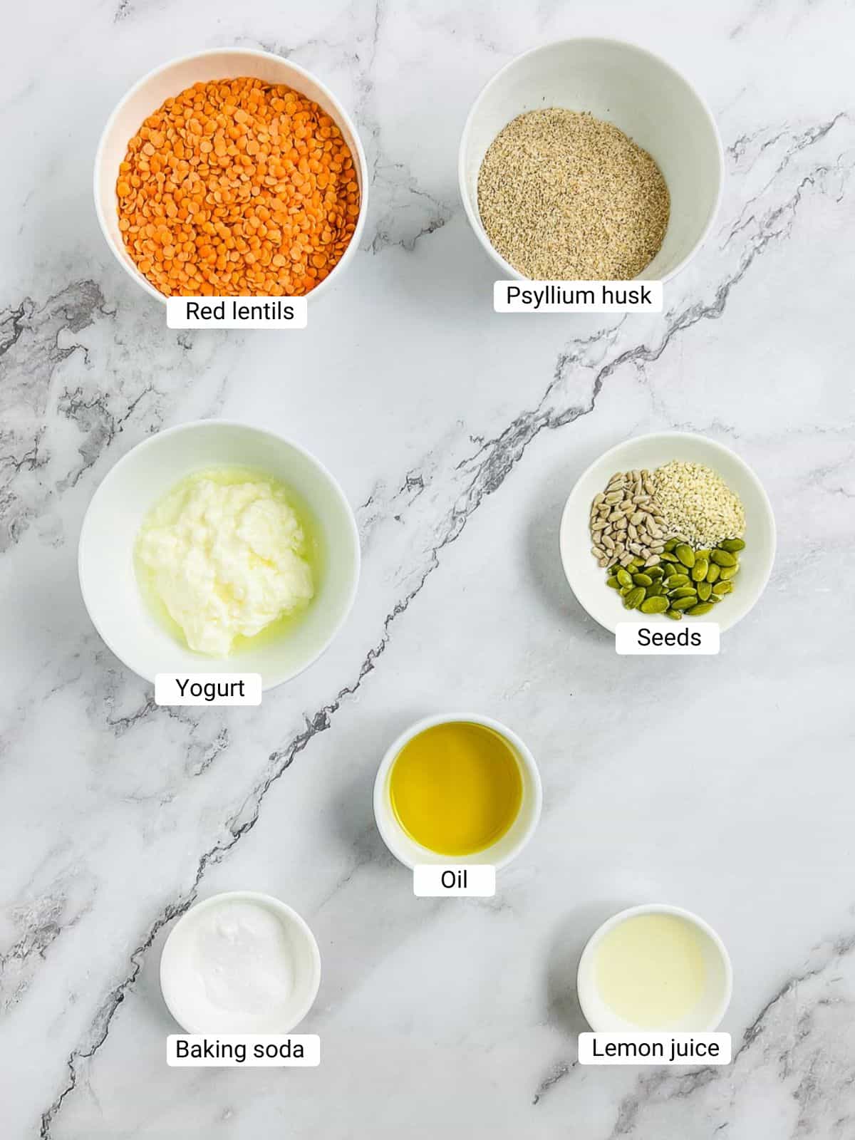 Ingredients to make lentil bread rolls on a marble surface.