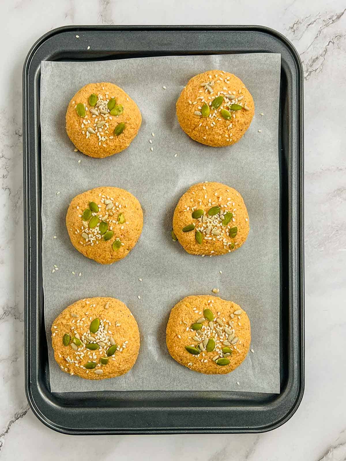 Shaped rolls placed on a lined baking sheet.