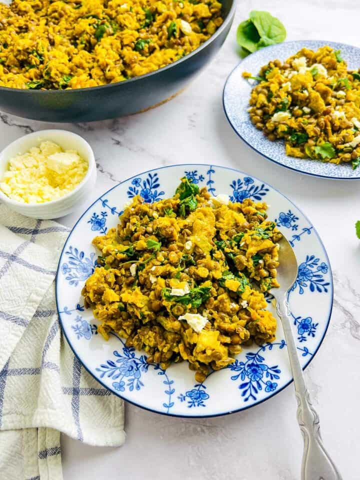 Lentil and eggs breakfast scramble served in blue plates.