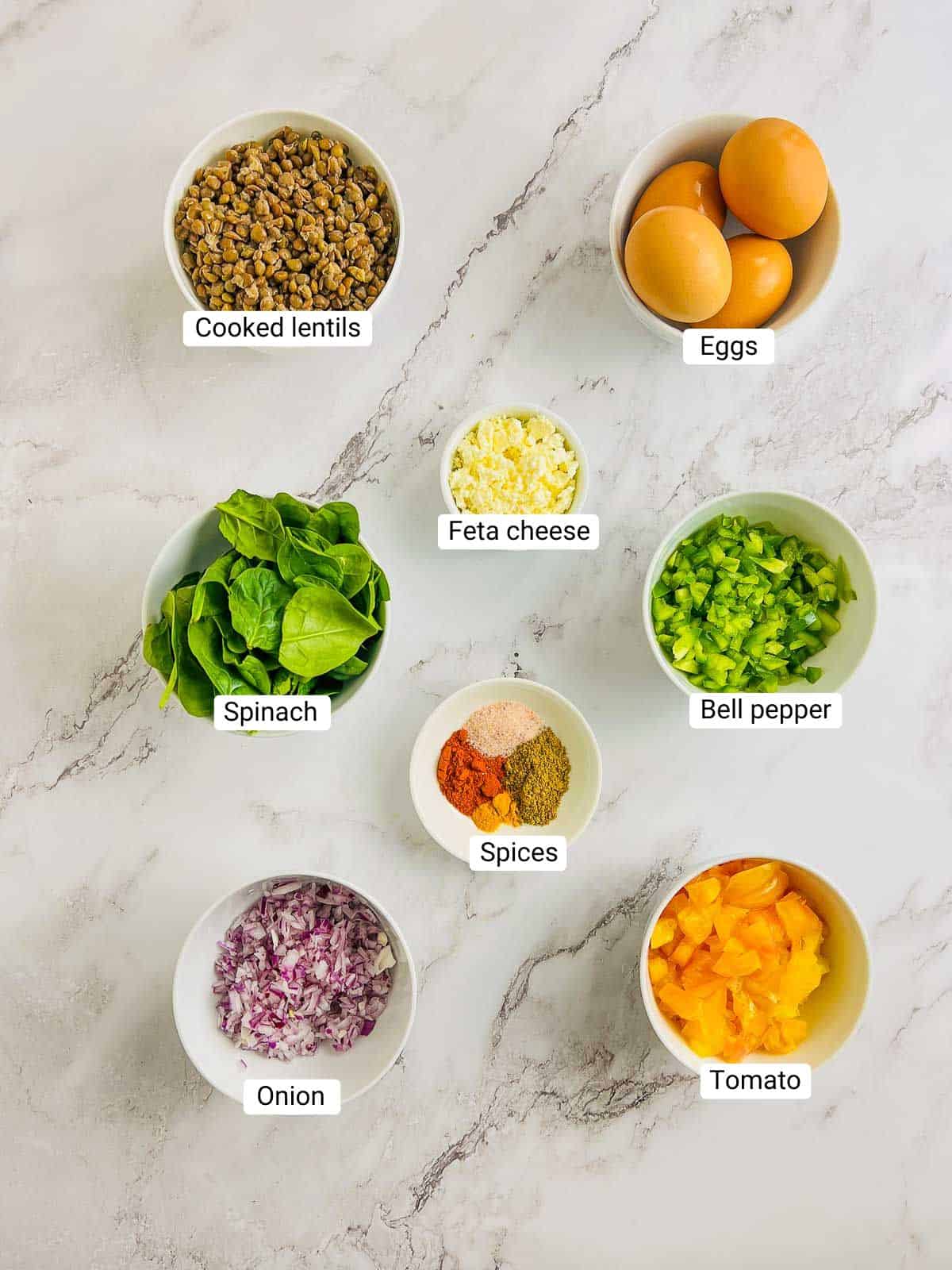 Ingredients to make lentil and eggs breakfast scramble on a marble surface.