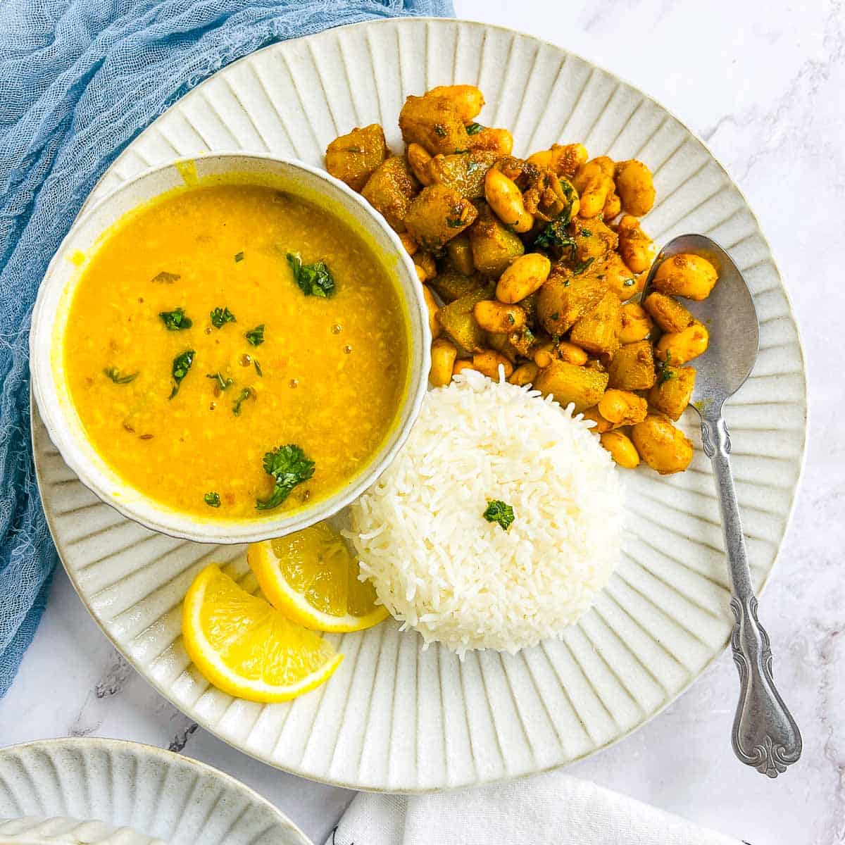 Chayote squash served with rice and dal on a white plate.