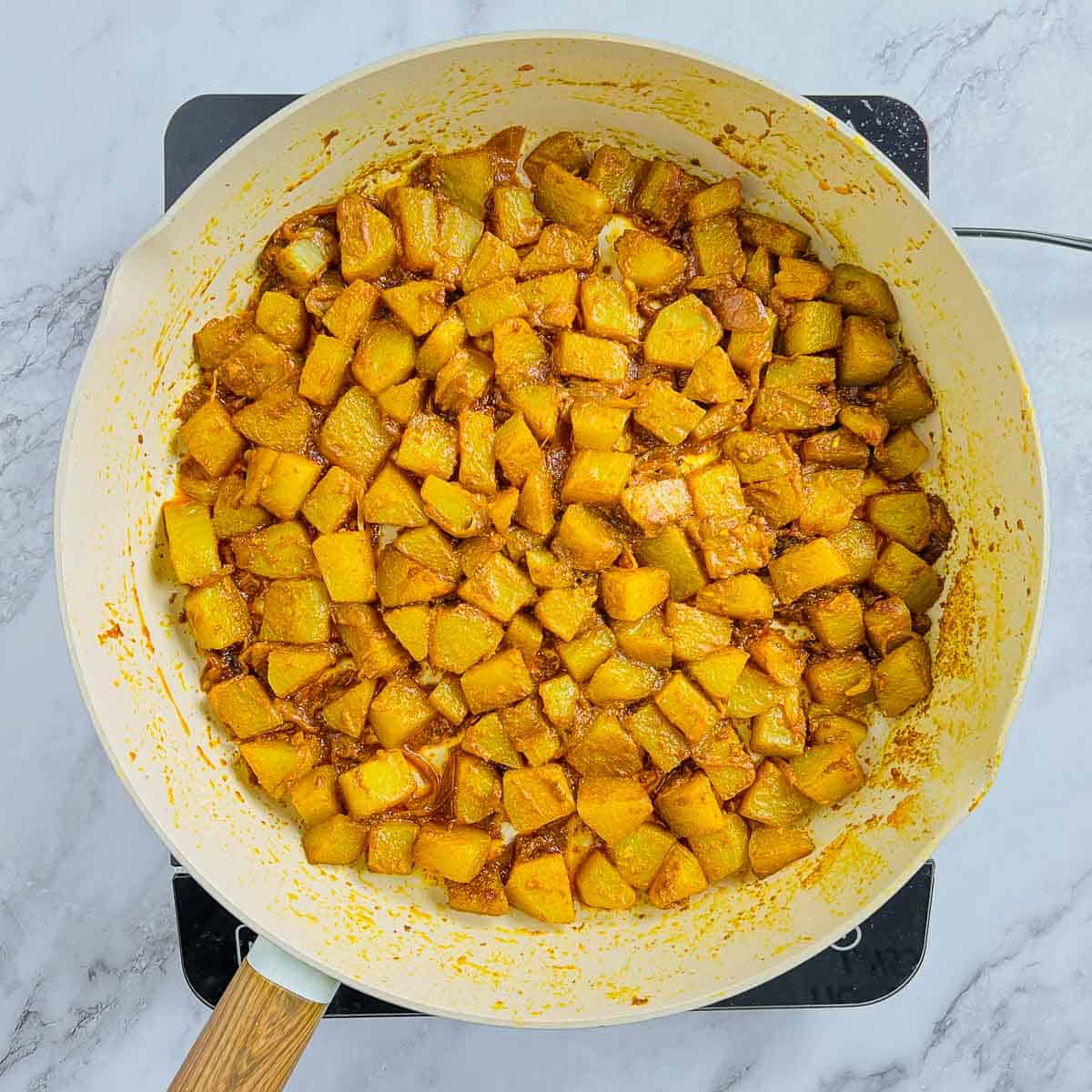 Cooked chayote squash in the onion masala in frying pan.