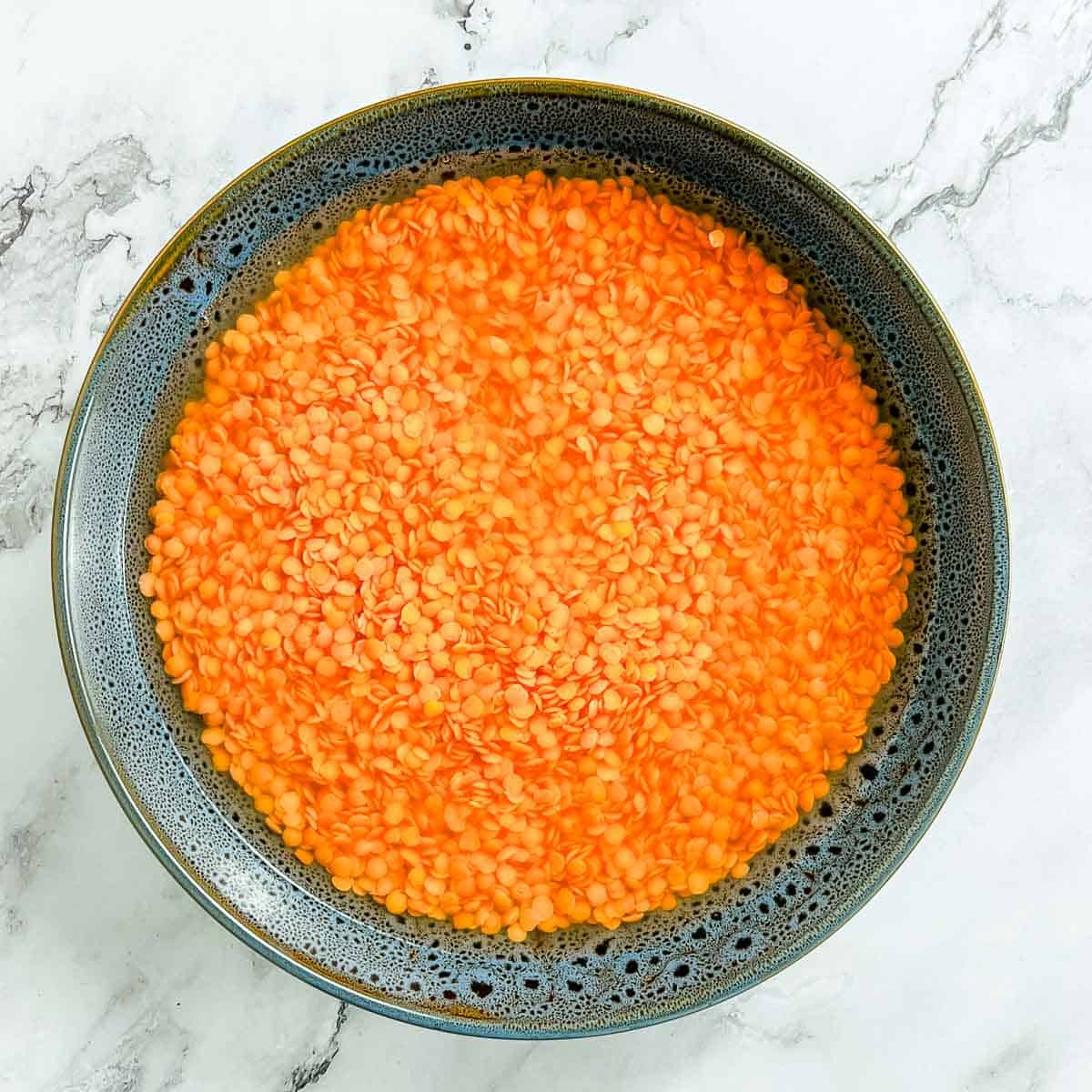 Soaked red lentils in a wide bowl.