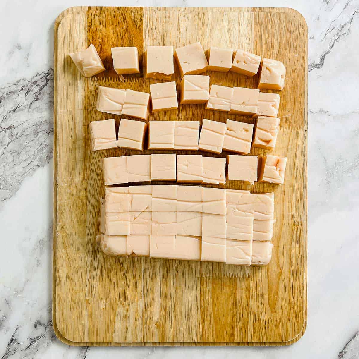 Red lentil tofu cut into cubes on a wooden board.