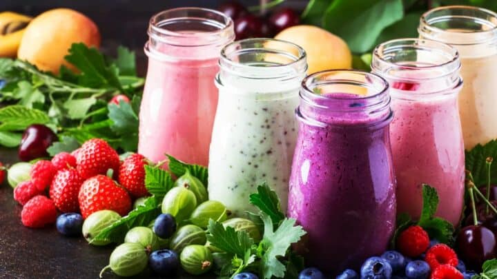 Jars of smoothies with fruits in the background.