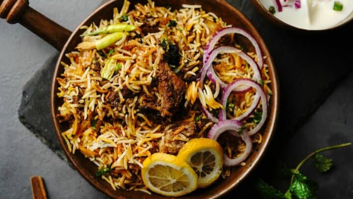 Biryani garnished with lemon and onion rings.