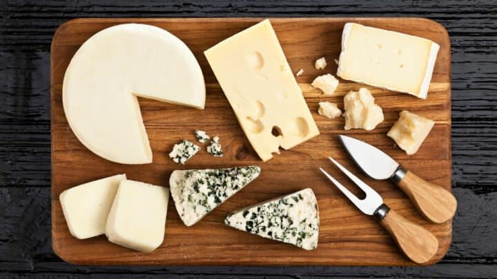 Various types of cheese on a wooden board.