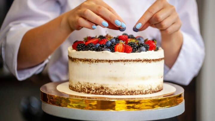 Woman decorating a cake.