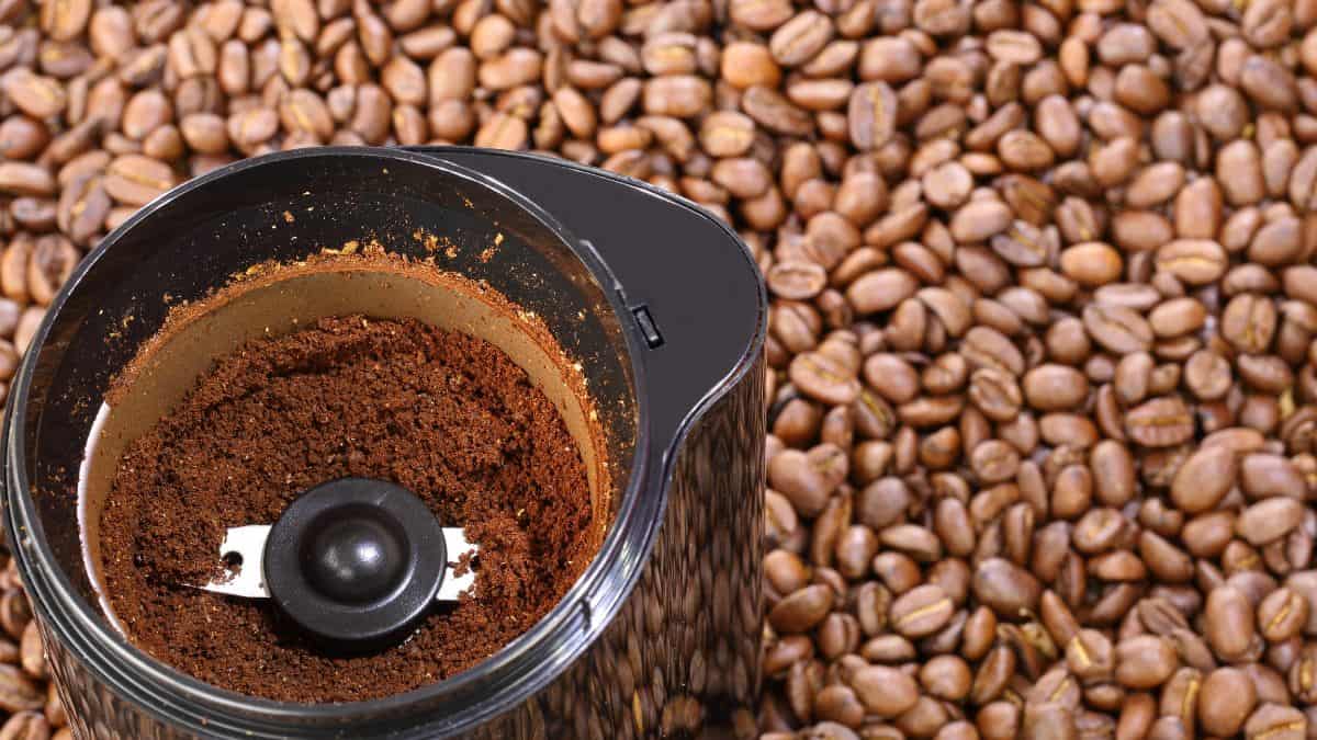 Coffee grinder with ground coffee and coffee beans.