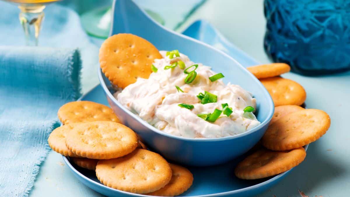 Onion dip in a blue bowl served with crackers.