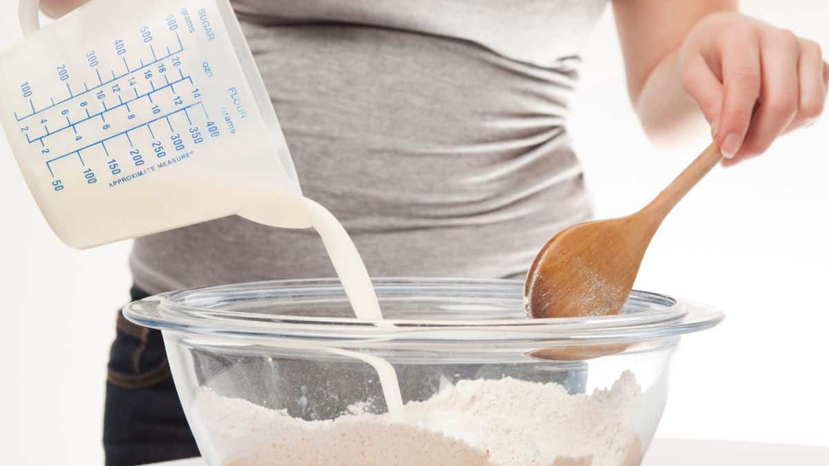 Person adding buttermilk into cake batter.