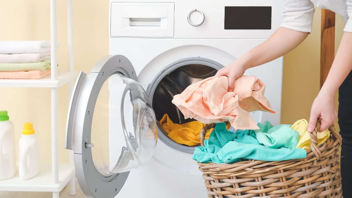 Woman taking out laundry from washing machine.