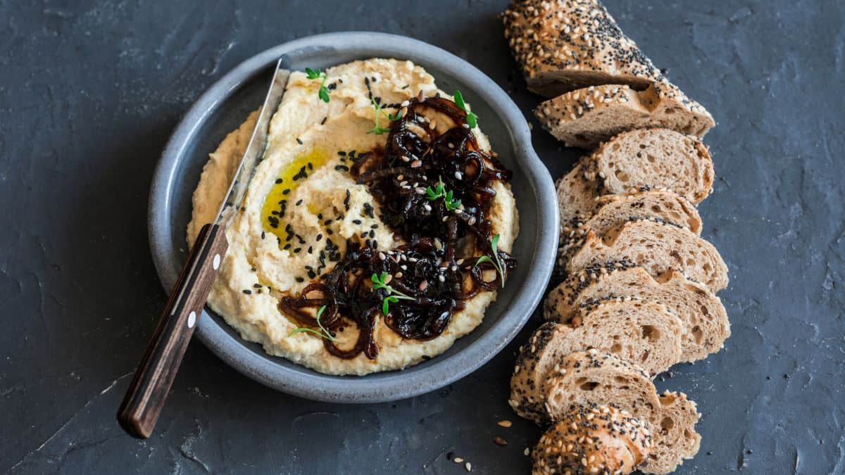 A bowl of caramelized hummus served with rustic bread.