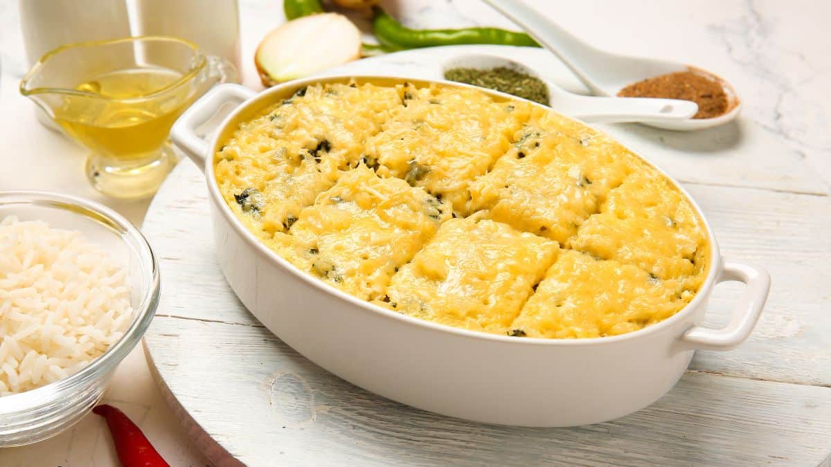 Rice casserole on a marble board with cooked rice in the background.