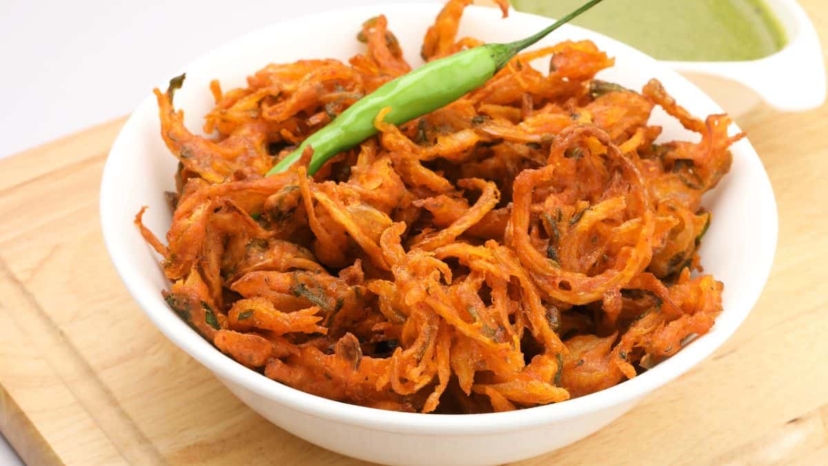 A bowl of onion pakora garnished with green chili.