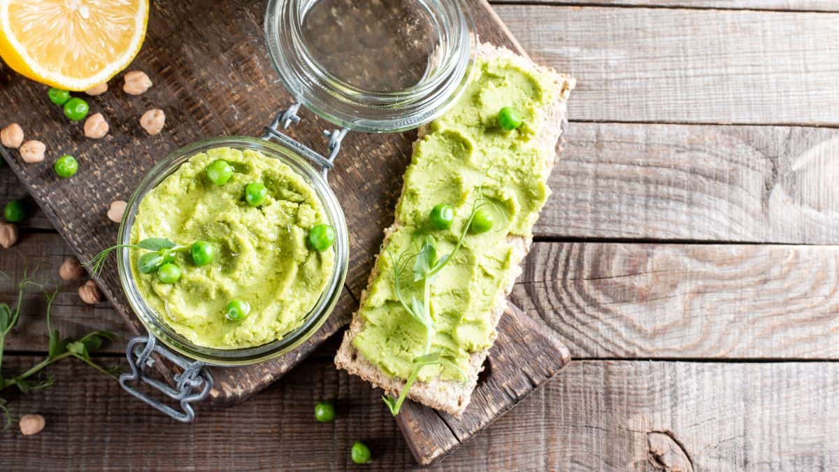 Green hummus in a jar and spread on a cracker,