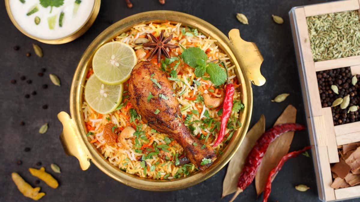 Bombay biryani in a bowl with spices in the background.