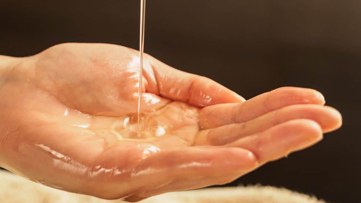 Person pouring massage oil on hand.