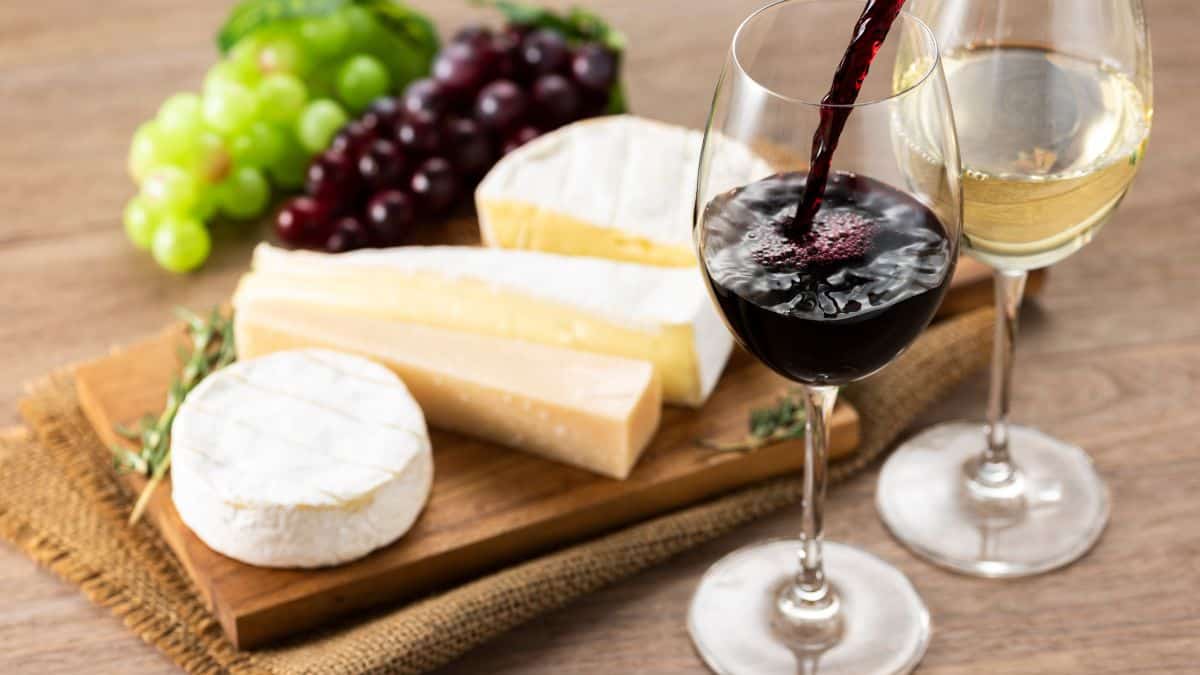 Wine and cheese on a wooden table.