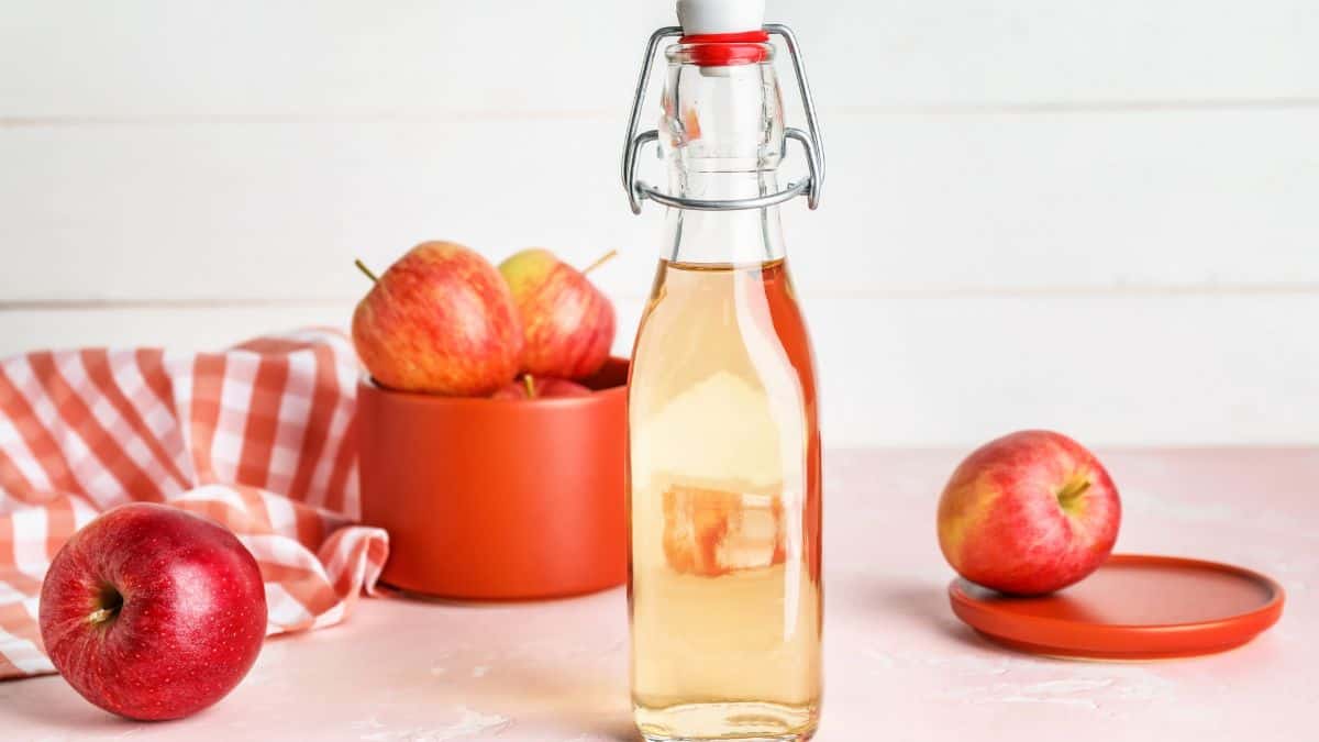 ACV in a bottle with apples in the background.