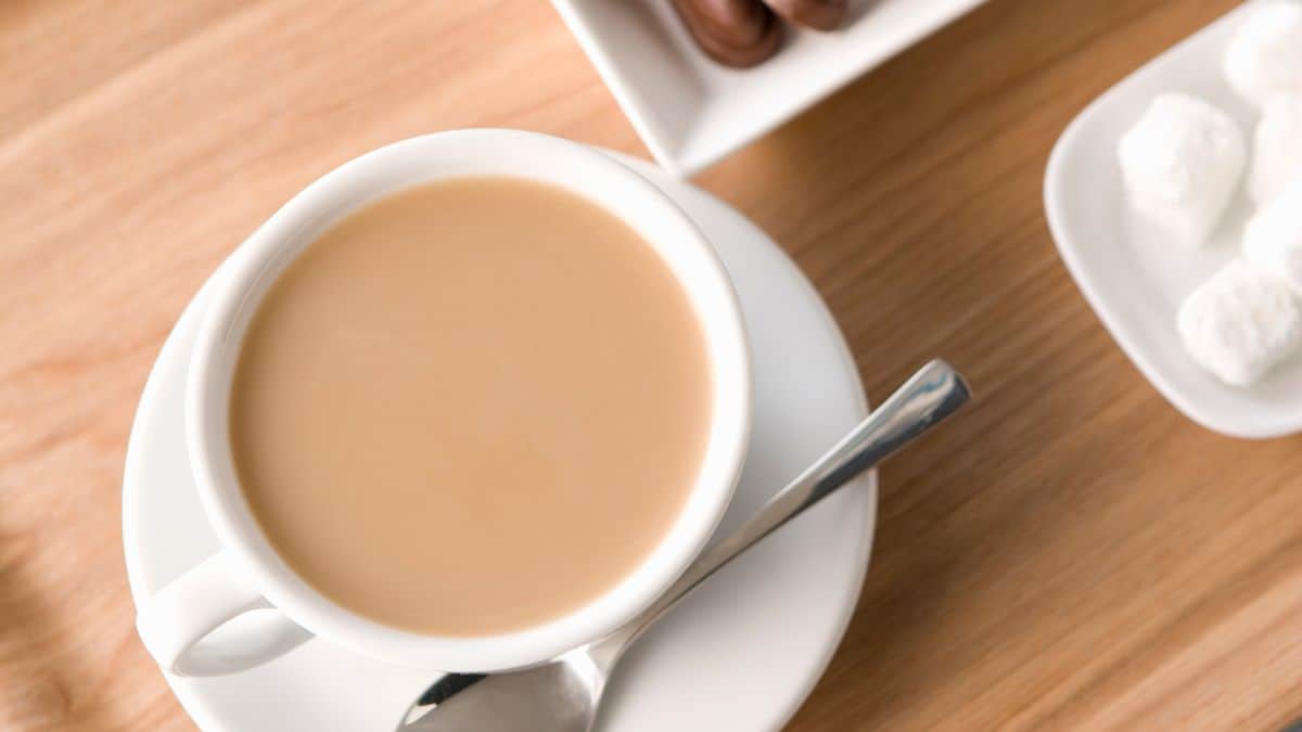 A cup of cafe au lait with bread in the background.