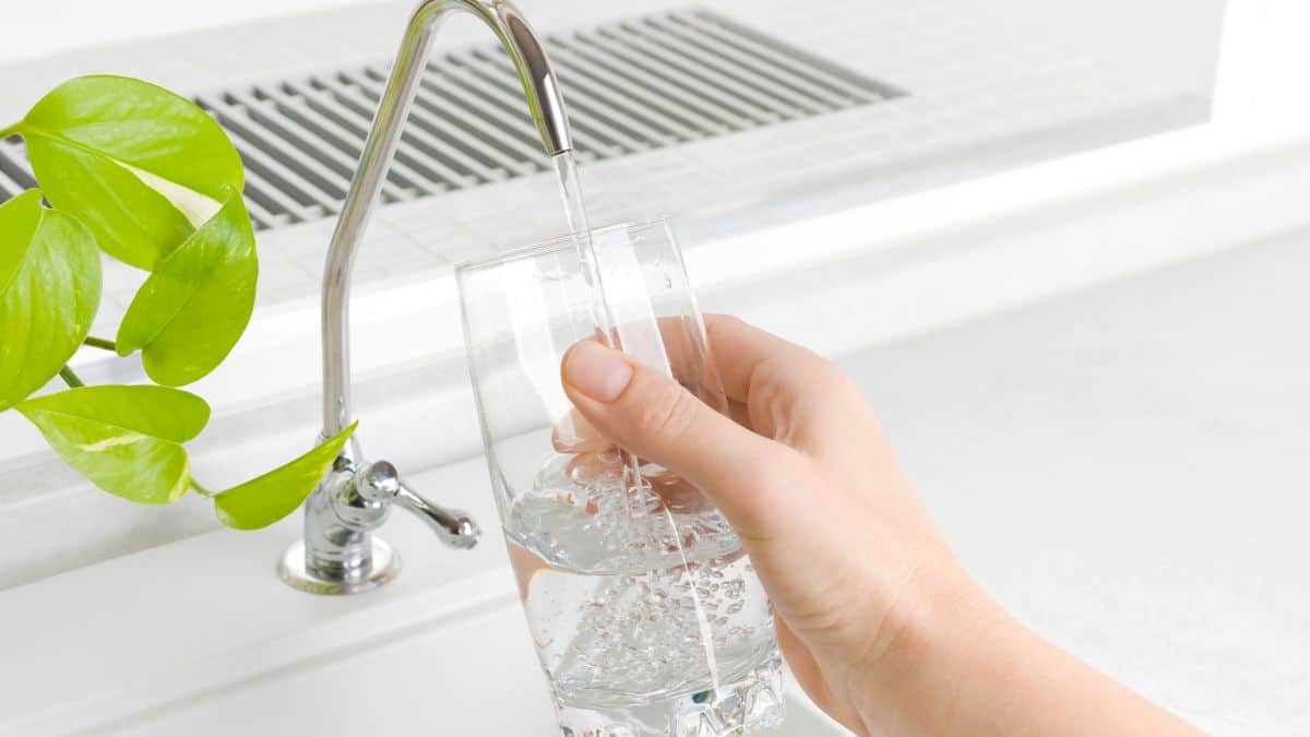 Person filling a glass of water from a water filter.